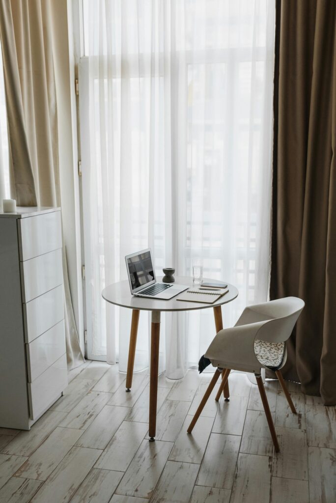 Petite table avec une chaise devant des voilages avec tentures couleur kaki