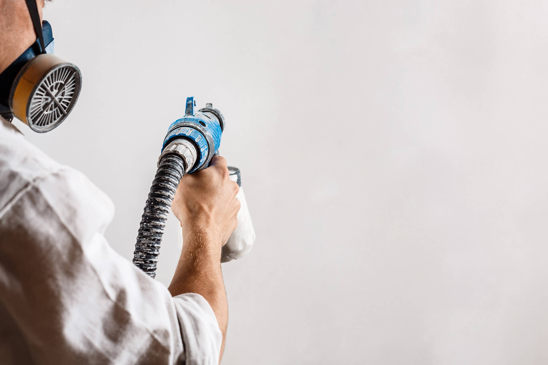 worker-painting-wall-with-spray-gun-white-color